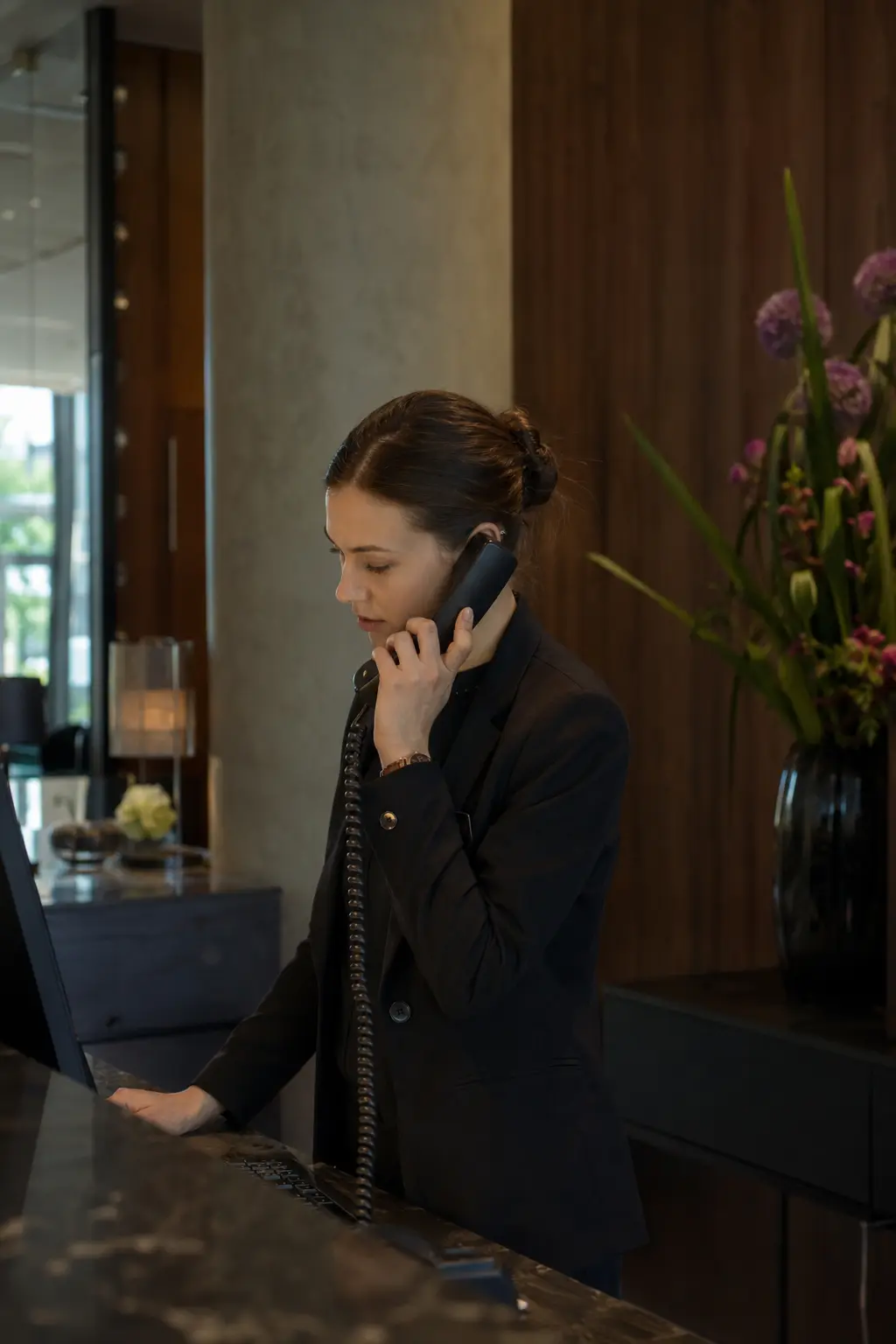 Pracowniczka recepcji nowoczesnego hotelu podczas rozmowy telefonicznej